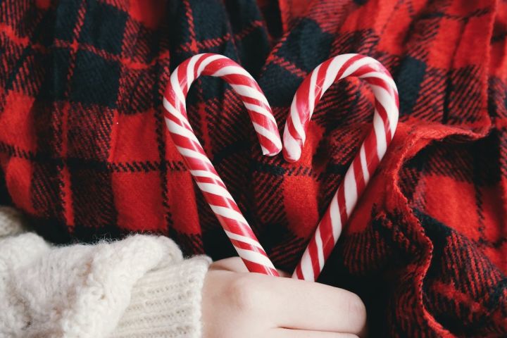 Candy canes positioned in a heart shape with red and black tartan background.