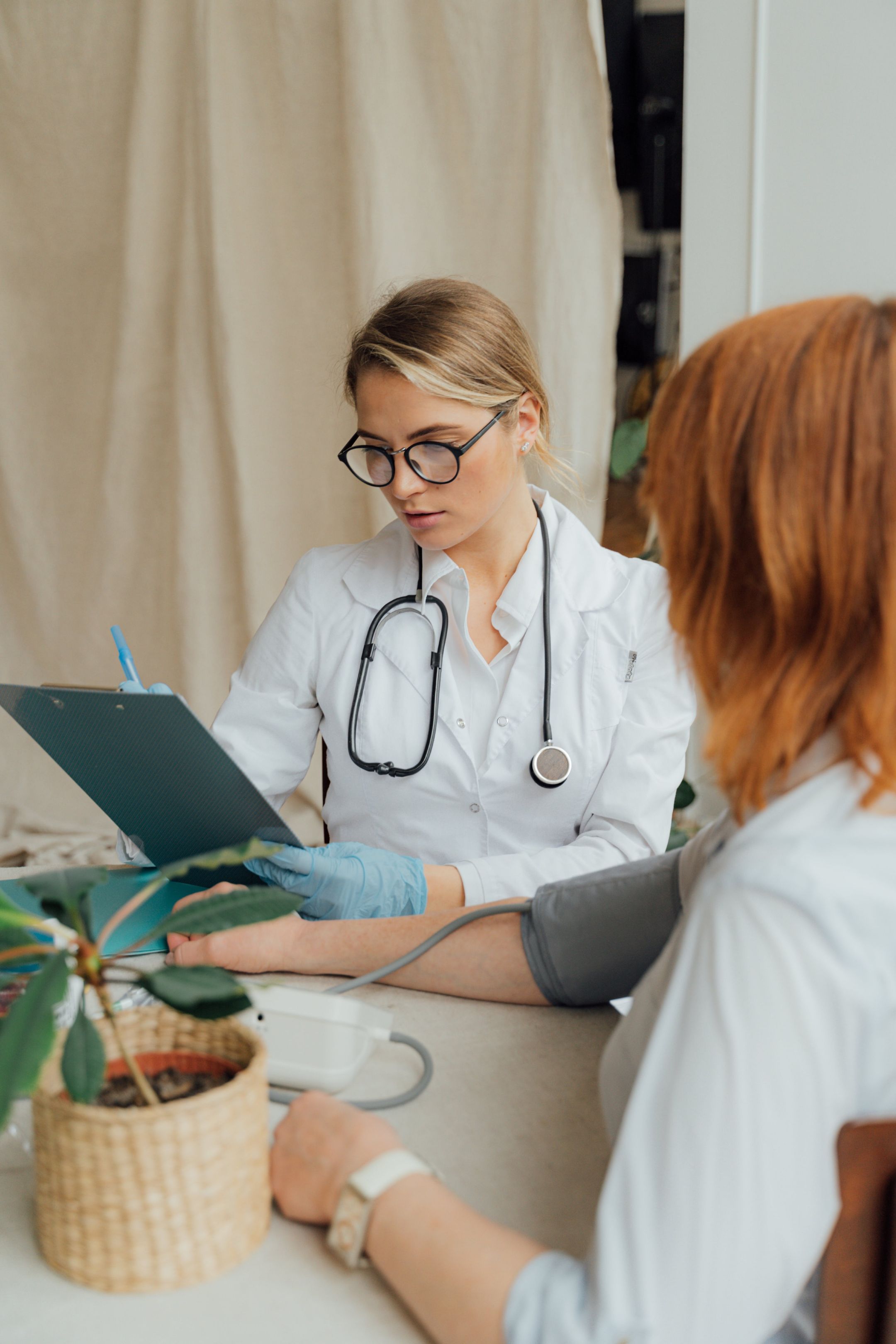 woman doctor examining patient, checking blood pressure.